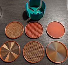 four different types of metal discs sitting on a table next to a cup and container