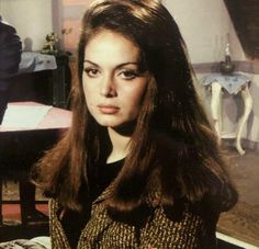 an old photo of a woman with long brown hair and blue eyes sitting in front of a table