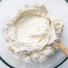 a glass bowl filled with whipped cream next to a wooden spoon