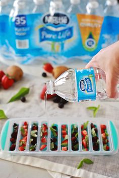 someone is pouring water into small trays filled with fruits and vegtables