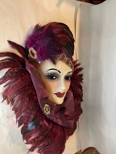 a mannequin head with feathers and jewels on it's face is shown