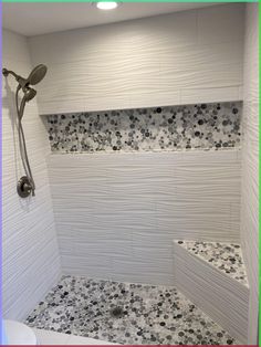 a white tiled shower with black and white flowers on the wall