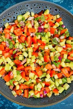 a bowl filled with chopped vegetables on top of a blue table cloth next to a knife and fork