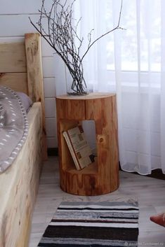 a small wooden table with a book on it in front of a white curtained window