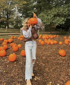 a woman standing in a field full of pumpkins