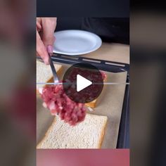 a person is cutting into a sandwich with a knife and some meat on the side