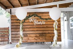 an outdoor wedding venue with white balloons and greenery at the entrance to the reception area