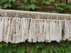 an old lace curtain hanging on a vine covered wall