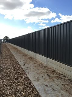 a long metal fence next to a dirt road