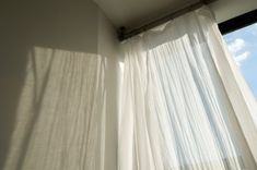 an open window with white curtains and a curtain rod