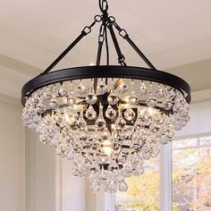 a chandelier hanging from the ceiling in a dining room with windows and white walls