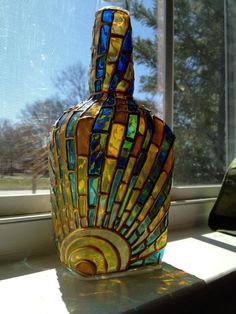 a decorative glass bottle sitting on top of a window sill next to a window