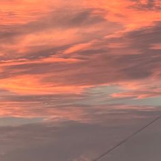 an airplane is flying in the sky with pink and orange clouds behind it at sunset