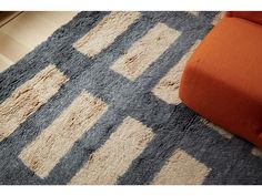 an orange chair sitting on top of a rug next to a white and blue floor