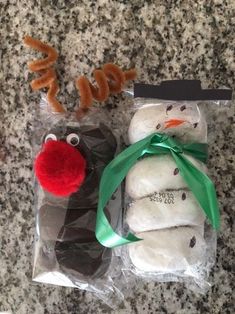 two frosted snowman cookies in plastic bags with green ribbon and reindeer nose on top