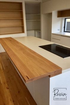 an empty kitchen with white counter tops and wooden flooring