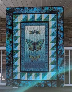 a blue and green quilt with a dragonfly on it