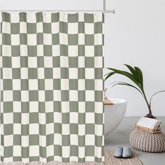 a white and gray checkered shower curtain next to a potted plant on the floor