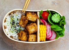 a bento box filled with rice, vegetables and tofu