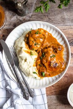 a white plate topped with mashed potatoes covered in gravy