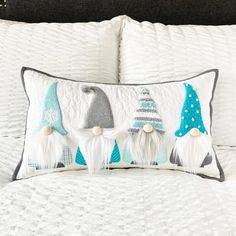 a white bed topped with pillows and two gnomes on top of each other's head