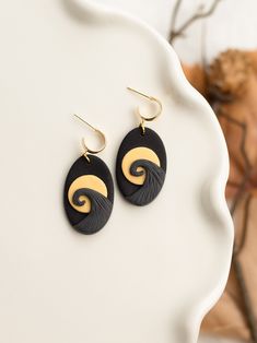 black and gold earrings with swirl design on them