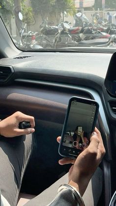 a person sitting in a car holding a cell phone and looking at something on the screen