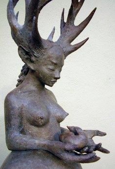 a statue of a woman with antlers on her head and hands in her lap