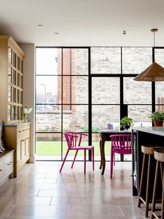 a kitchen with lots of windows and pink chairs