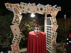 a table topped with a cake covered in playing cards on top of a lush green field