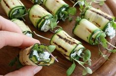 someone is holding up some food on a wooden platter with spinach and feta cheese