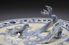 a blue and white dragon figurine sitting on top of a plate