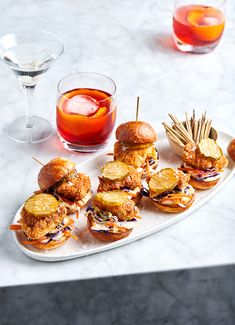 small sandwiches and drinks on a white tray with marble countertop in the foreground