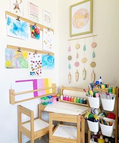 a child's art room with wooden desks, chairs and paintings on the wall