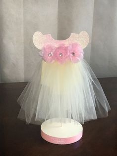 a pink and white tulle skirt with flowers on the bottom is sitting on a table