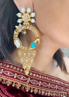 Elevate your style with our statement earrings, featuring intricate peacock designs adorned with blue Feroza stones and polki pearls. These long earrings are perfect for adding a touch of elegance and sophistication to any outfit. Elegant Peacock Design Chandelier Earrings For Festive Occasions, Elegant Festive Chandelier Earrings With Peacock Design, Elegant Chandbalis With Peacock Design For Diwali, Festive Kundan Danglers With Peacock Design, Chandbali Danglers With Peacock Design, Kundan Danglers With Peacock Design, Elegant Kundan Jhumkas With Peacock Design, Kundan Chandbali Danglers With Peacock Design, Party Bridal Chandbali Earrings With Peacock Design