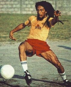 a man kicking a soccer ball on top of a field