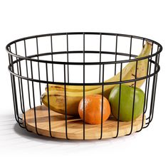 a metal basket filled with fruit sitting on top of a wooden cutting board in front of a white background