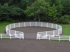 a white fenced in horse pen with trees in the background