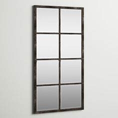 a mirror mounted to the side of a white wall next to a black framed window