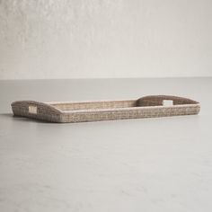 an empty wicker tray sitting on top of a white counter next to a wall