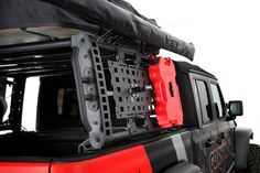 a red and black jeep is parked with its roof rack on it's back