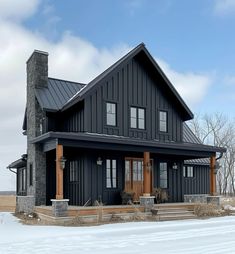 a large black house sitting on top of a snow covered field