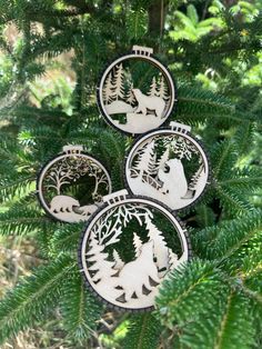 three ornaments are hanging from the branches of a tree with trees and animals on them