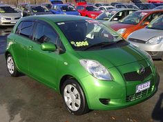 a small green car parked in a parking lot