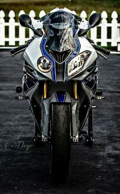 a motorcycle parked in front of a white picket fence