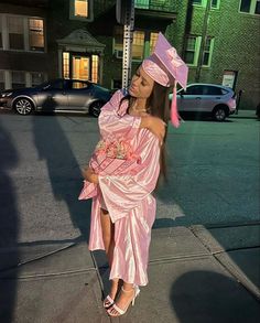 a woman in a pink dress and hat on the street