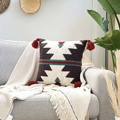 a couch with a blanket and pillows on top of it next to a potted plant