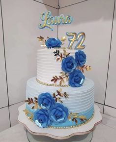 a white cake with blue flowers on top and the number twenty two in gold lettering