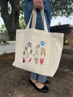 LIMITED EDITION- ONLY 8 AVAILABLE The summer tote or beach bag of your dreams is HERE! Icons of el Verano that bring summer vibes to any season☀️ 100% Cotton/ Multicolor design Embroidered with love by JZD in Brownsville, TX Pocket inside Measurements Tote bag: 14" x 14"  Depth: 5.5" Handles: 11" Trendy Canvas Bag For Beach Season, Casual Embroidered Beach Bag, Trendy Embroidered Canvas Bag For Travel, Casual Embroidered Tote Beach Bag, Trendy Embroidered Summer Bag, Embroidered Canvas Bag Casual Summer Style, Embroidered Casual Canvas Bag For Summer, Casual Embroidered Canvas Bag For Summer, Summer Embroidered Canvas Shoulder Bag